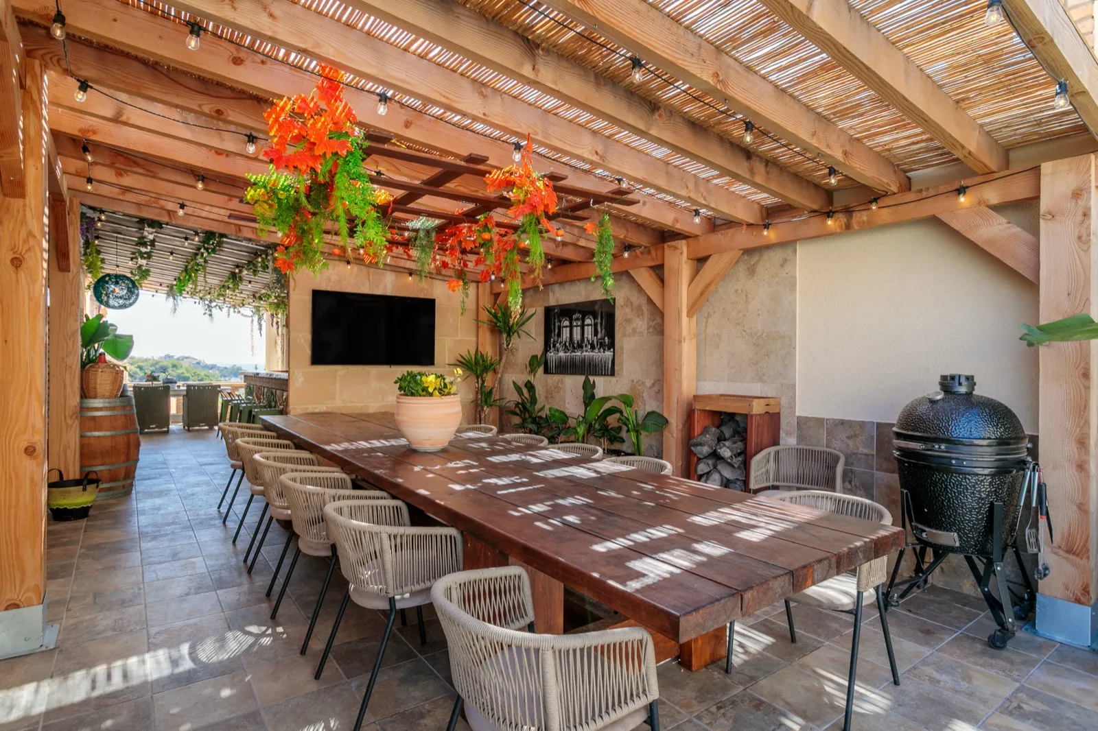 Overdekte lounge met lange eettafel en kamado-barbecue